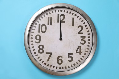 Photo of Stylish analog clock hanging on light blue wall