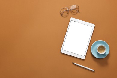 Modern tablet, glasses, stylus and cup of coffee on orange background, flat lay. Space for text