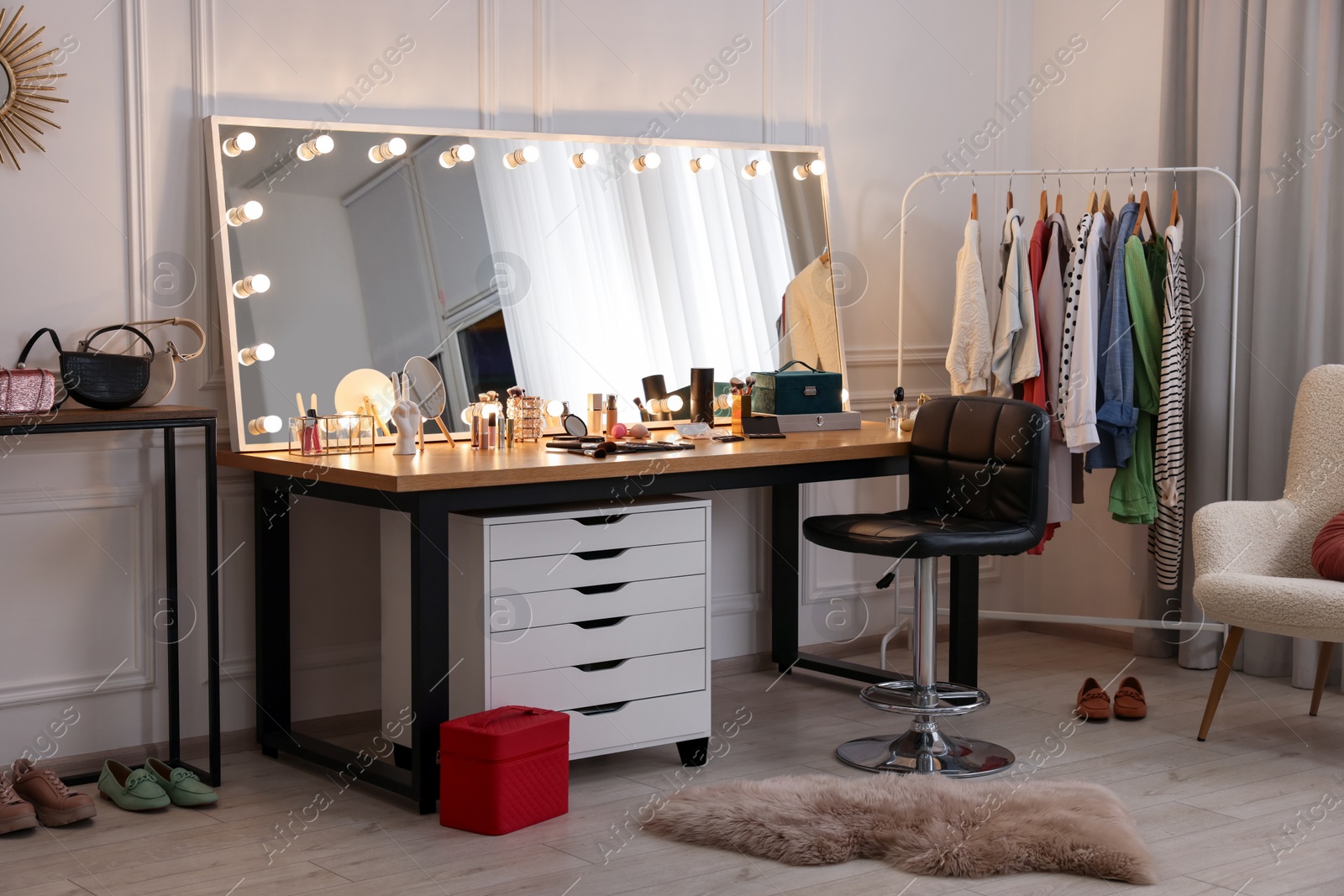 Photo of Makeup room. Stylish dressing table with mirror, chair and clothes rack