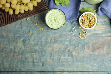 Photo of Flat lay composition with green buckwheat smoothie on light blue wooden table, space for text