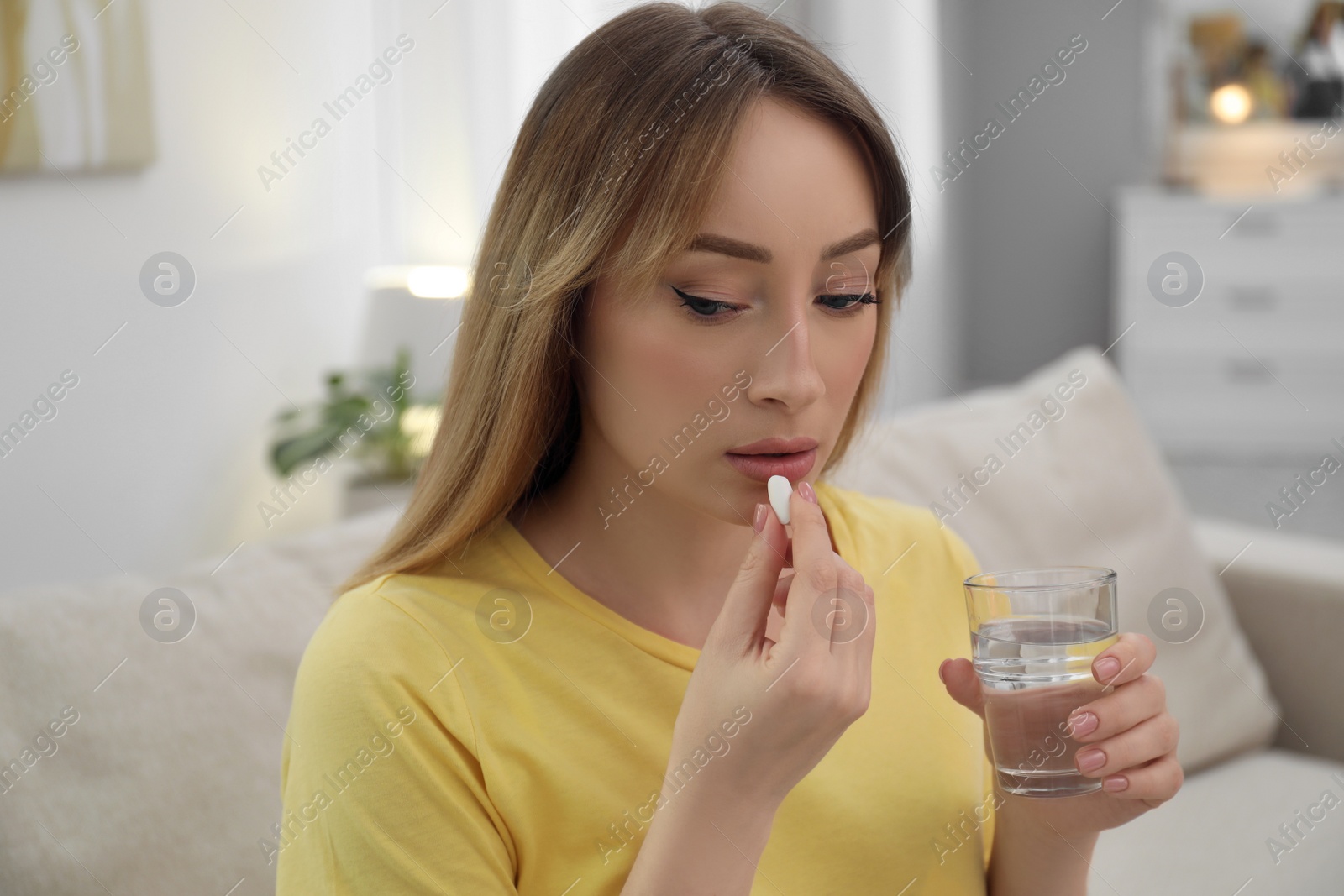 Photo of Young woman taking abortion pill at home