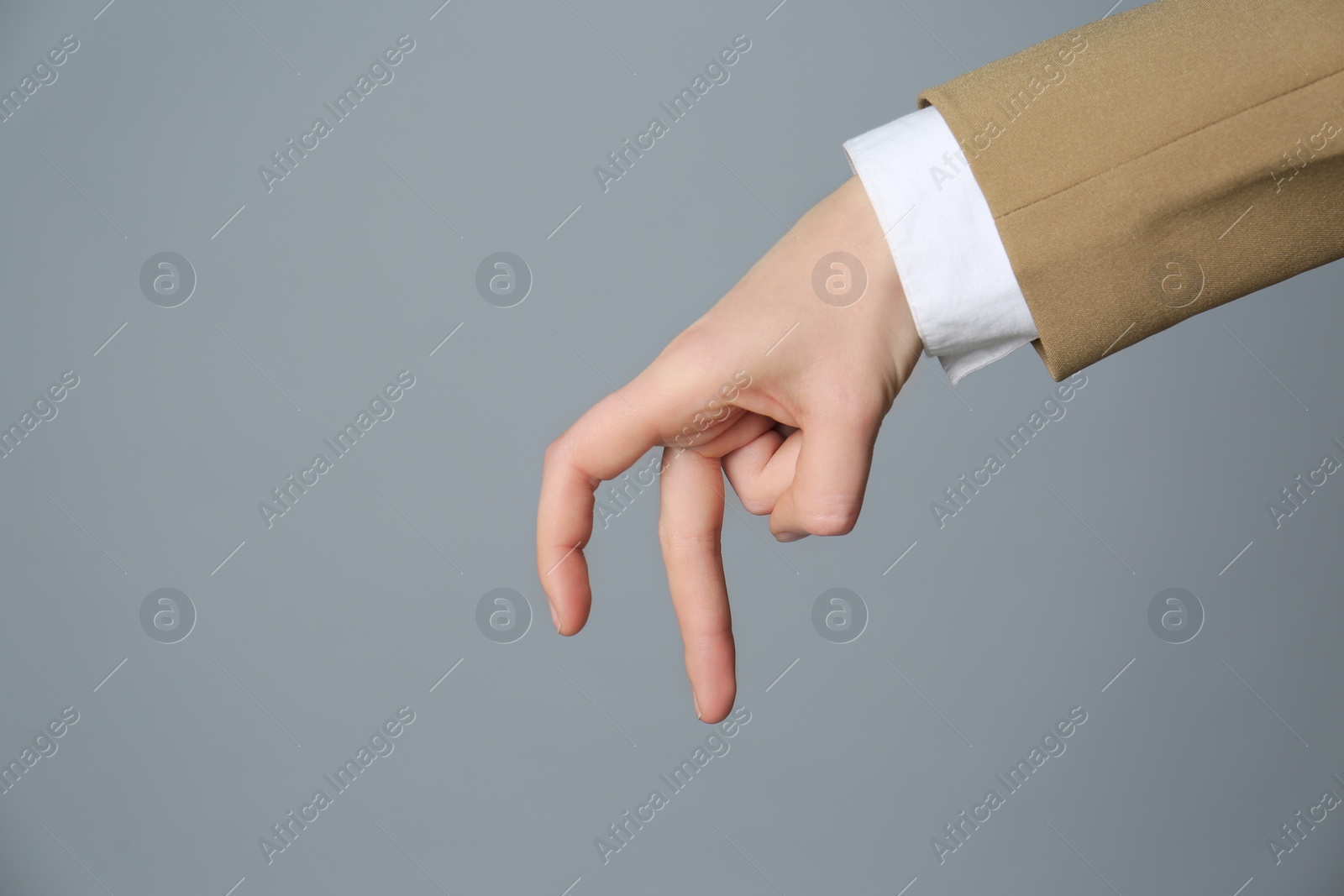 Photo of Businesswoman imitating walk with hand on grey background, closeup. Finger gesture