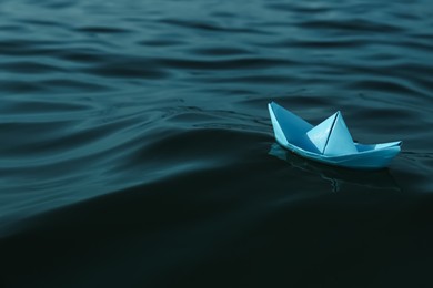 Photo of Light blue paper boat floating on river, space for text