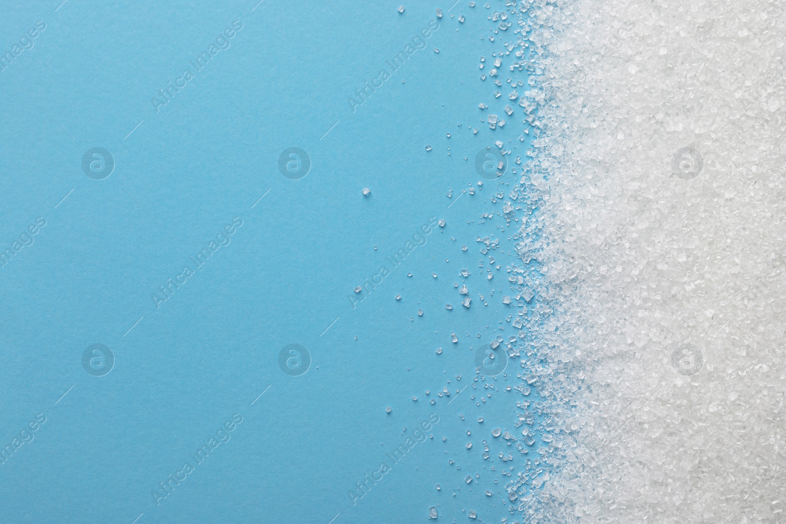 Photo of Granulated sugar on light blue background, top view. Space for text