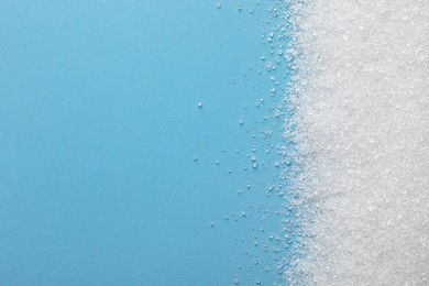 Photo of Granulated sugar on light blue background, top view. Space for text