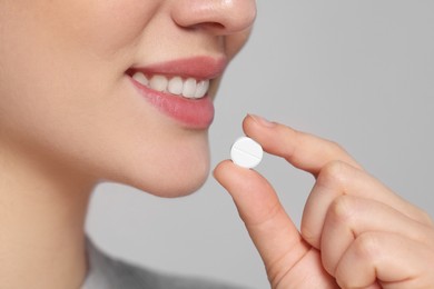 Photo of Woman taking pill on gray background, closeup