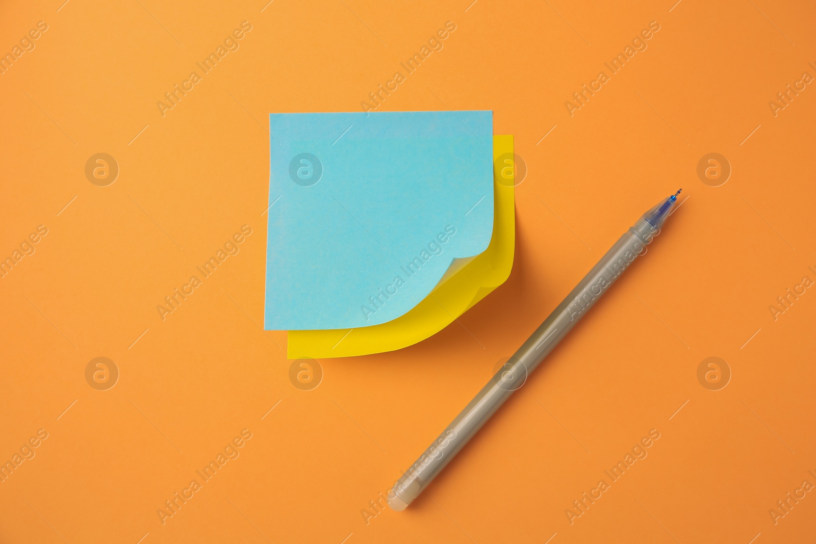 Photo of Blank paper notes and pen on pale orange background, flat lay