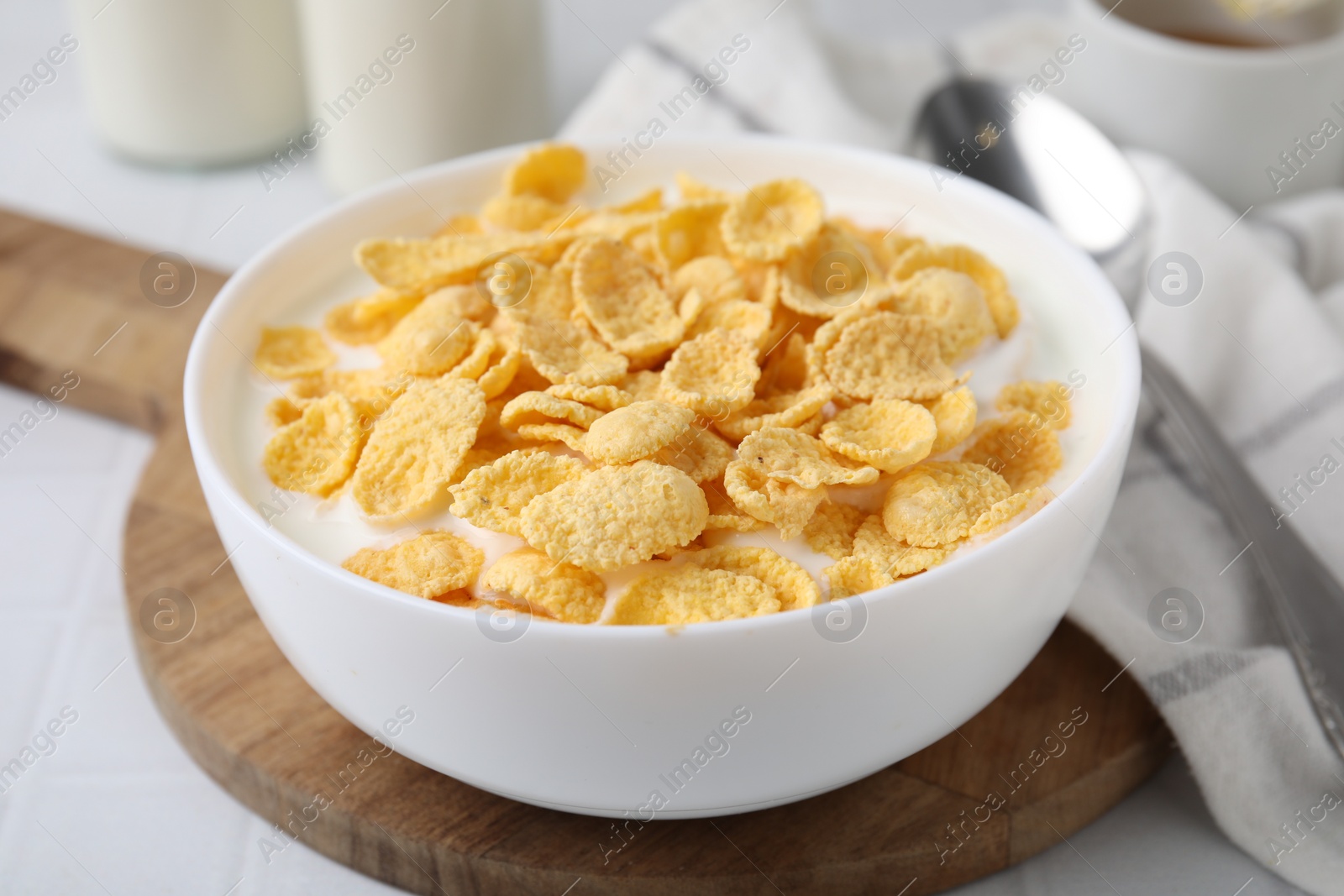 Photo of Breakfast cereal. Tasty corn flakes with milk in bowl on white table, closeup