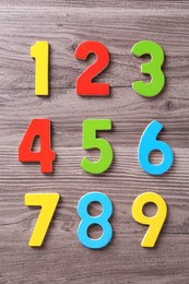 Photo of Colorful numbers on wooden school desk, flat lay