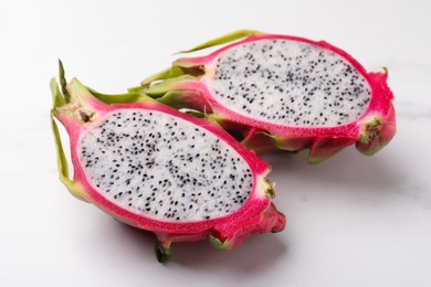 Halves of delicious dragon fruit (pitahaya) on white table