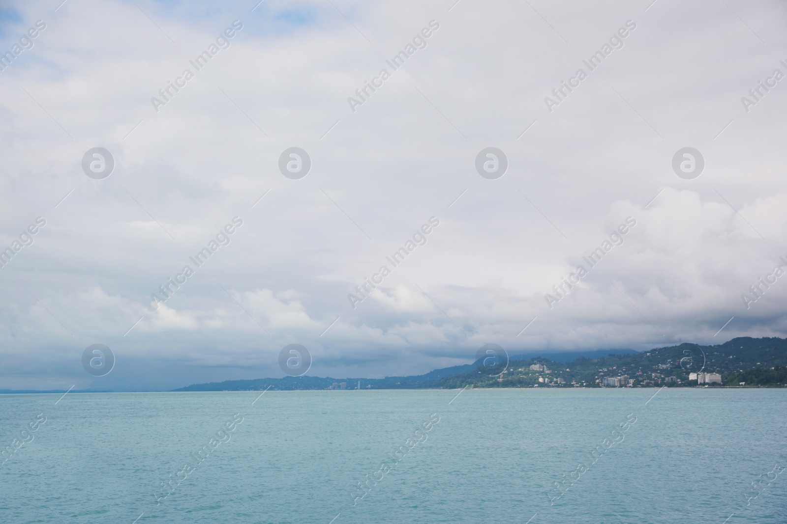 Photo of Picturesque view of sea with coastline and mountains under cloudy sky