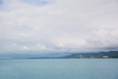 Photo of Picturesque view of sea with coastline and mountains under cloudy sky