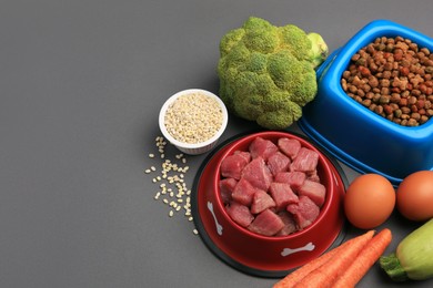 Photo of Raw meat in bowl and healthy products for pet on black background, above view. Space for text