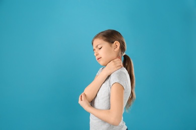 Photo of Little girl scratching neck on color background, space for text. Allergy symptoms