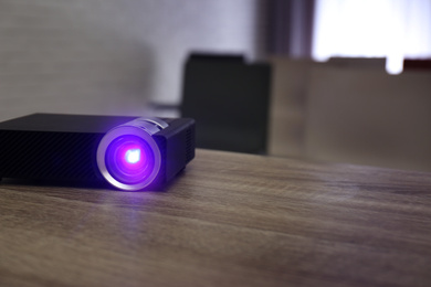 Modern video projector on wooden table in conference room. Space for text