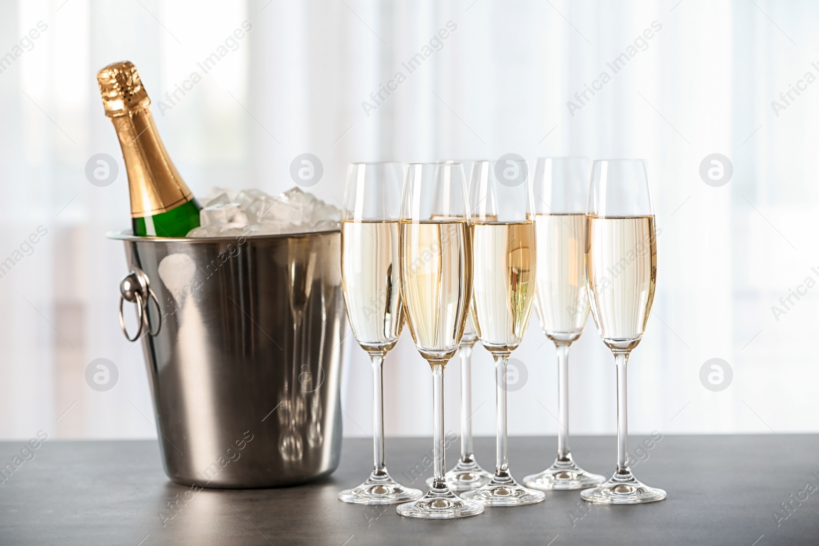 Photo of Glasses with champagne and bottle in bucket on table