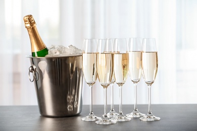 Photo of Glasses with champagne and bottle in bucket on table