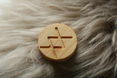 Photo of Wooden rune Inguz on light faux fur, closeup