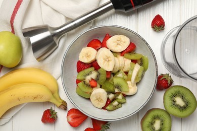 Photo of Hand blender kit, fresh fruits and strawberries in bowl on white wooden table, flat lay