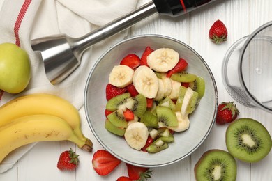 Hand blender kit, fresh fruits and strawberries in bowl on white wooden table, flat lay