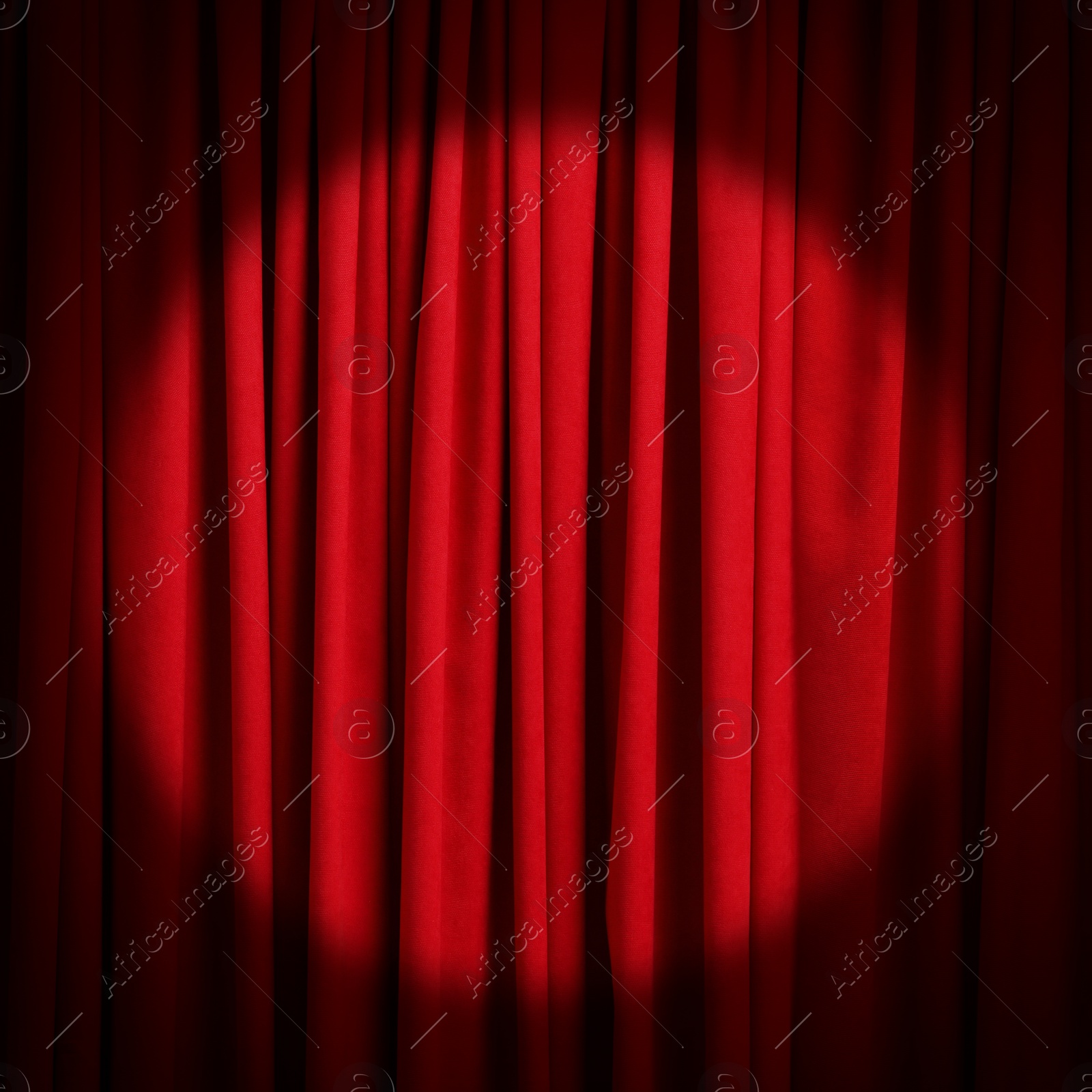 Image of Spotlight illuminating closed red stage curtains. Start of performance 