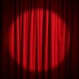Spotlight illuminating closed red stage curtains. Start of performance 