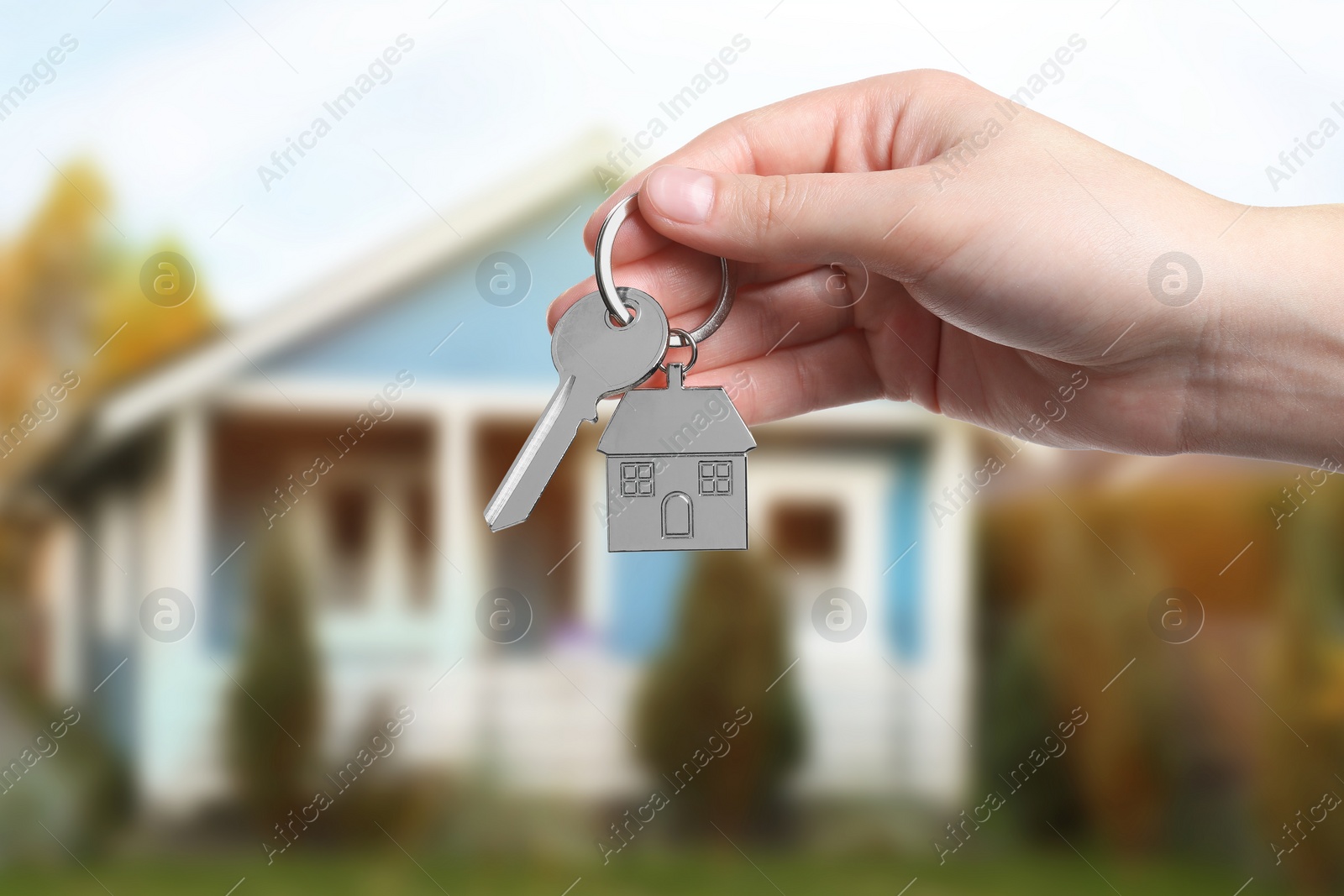 Image of Woman holding key near house outdoors, closeup