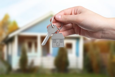 Image of Woman holding key near house outdoors, closeup