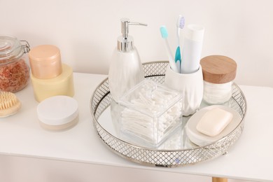 Photo of Different bath accessories and personal care products on table near white wall