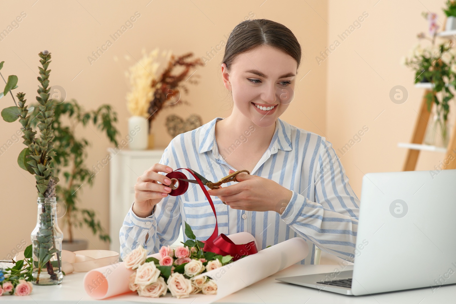 Photo of Woman making bouquet following online florist course at home. Time for hobby