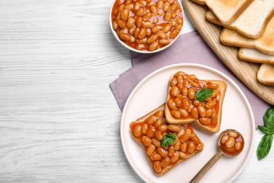 Photo of Toasts with delicious canned beans on white wooden table, flat lay. Space for text