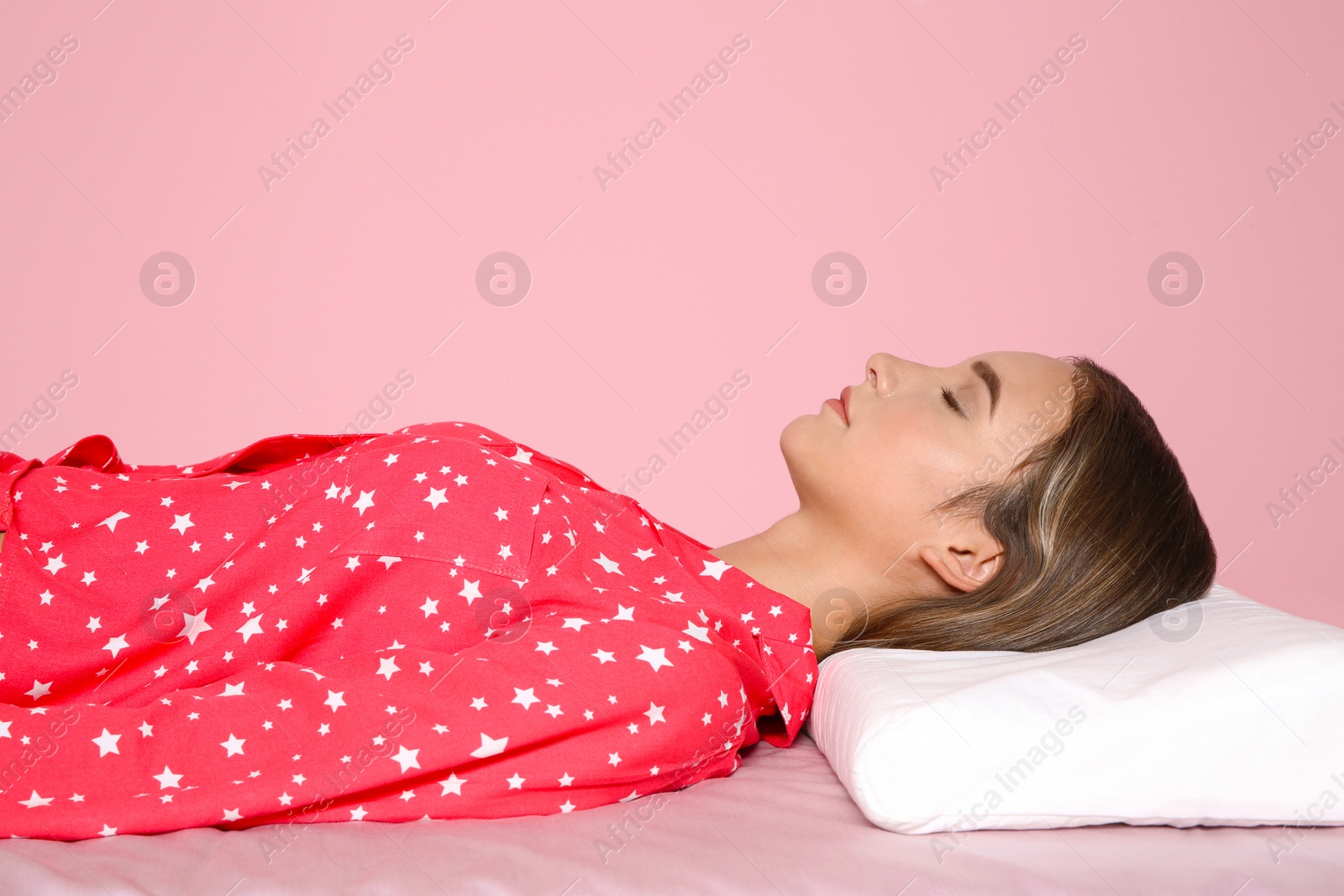 Photo of Beautiful teen girl sleeping with orthopedic pillow on bed against color background