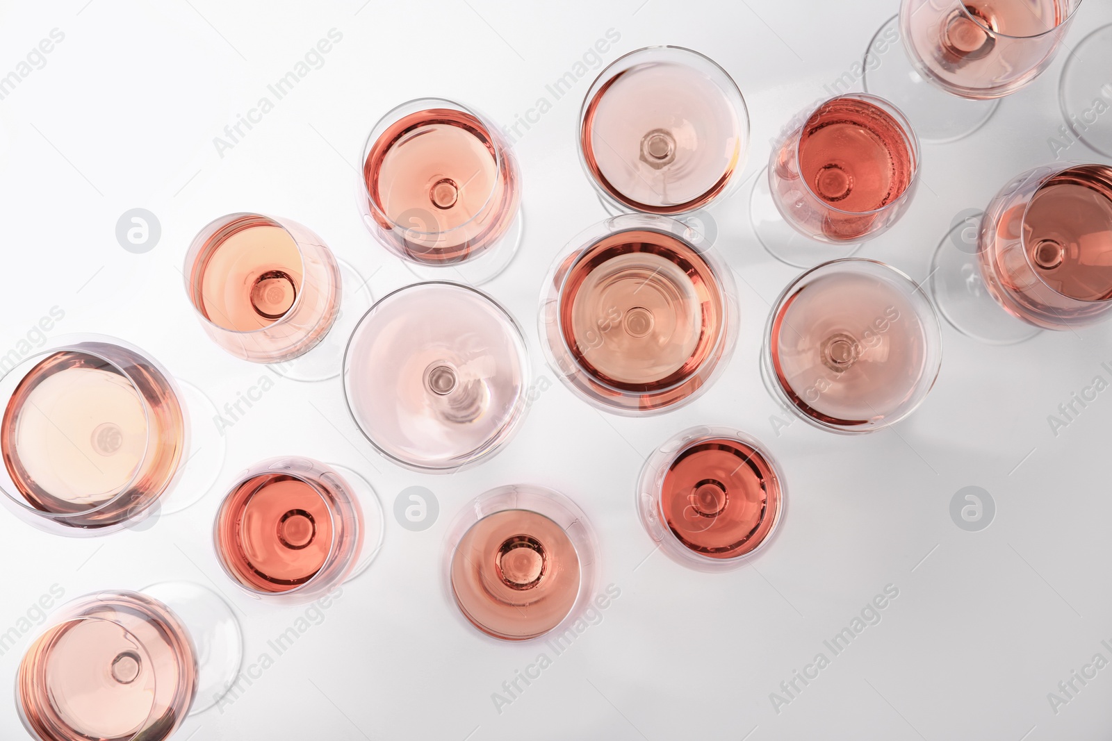 Photo of Different glasses with rose wine on white background, top view