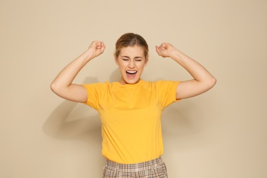 Photo of Happy young woman celebrating victory on color background