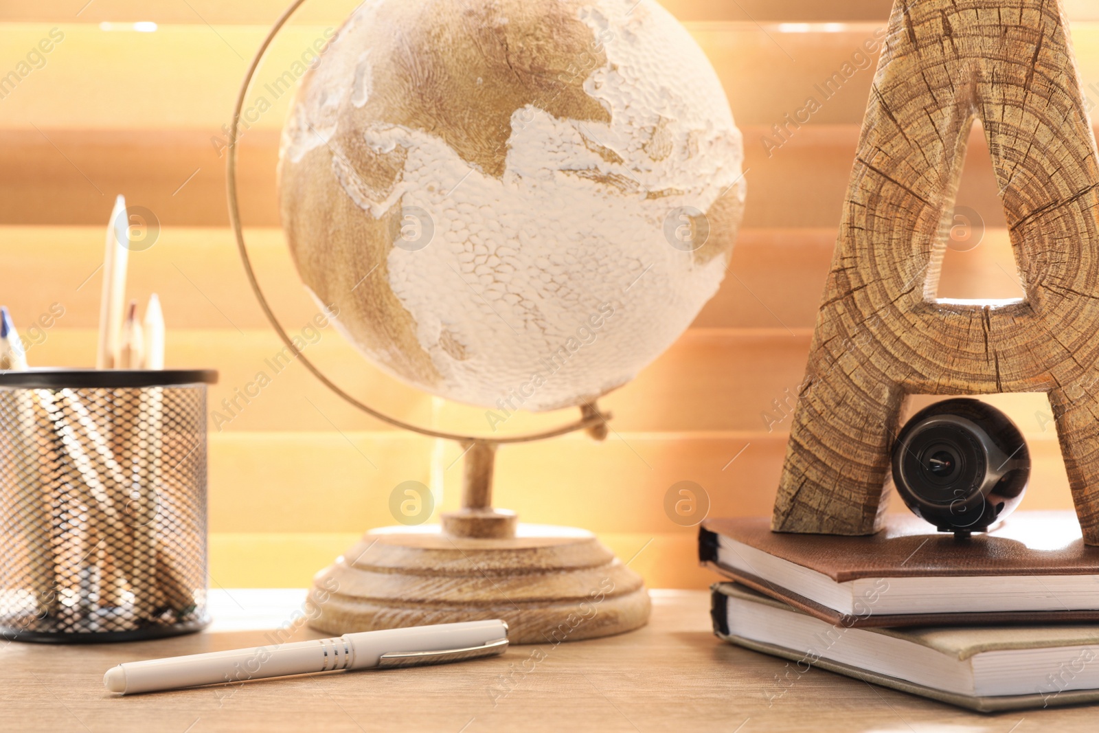 Photo of Small camera hidden among stationery on wooden desk against window indoors