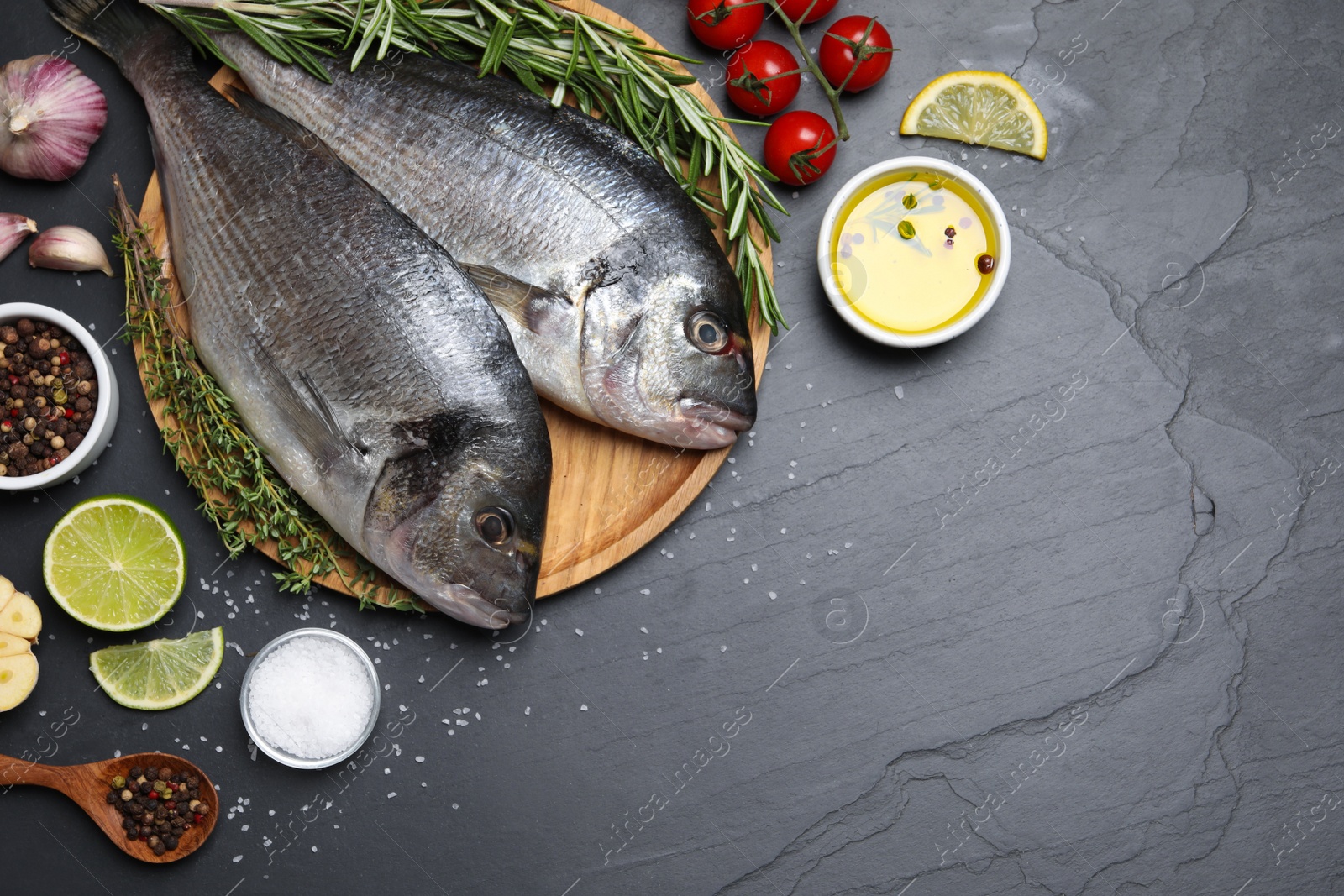 Photo of Flat lay composition with fresh raw dorado fish and ingredients on black table, space for text