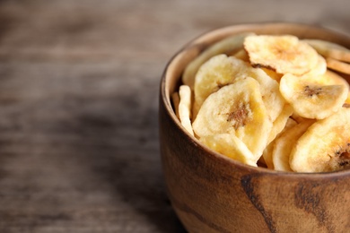 Bowl with sweet banana slices on wooden  table, space for text. Dried fruit as healthy snack