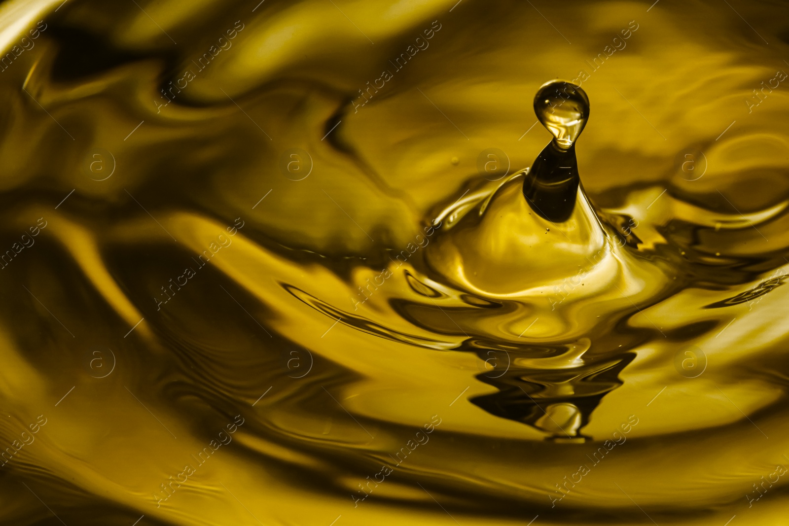 Image of Splash of golden oily liquid with drop as background, closeup