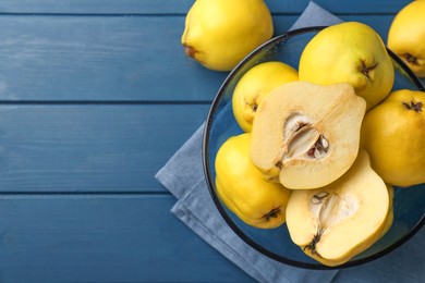 Tasty ripe quinces in bowl on blue wooden table, top view. Space for text