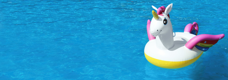 Image of Funny inflatable unicorn ring floating in swimming pool on sunny day, space for text. Banner design