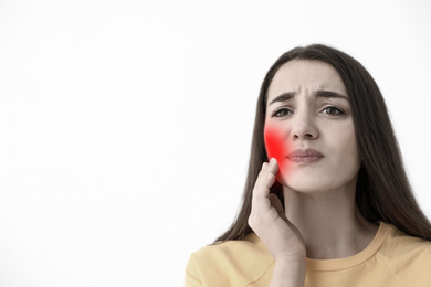 Young woman suffering from toothache on white background