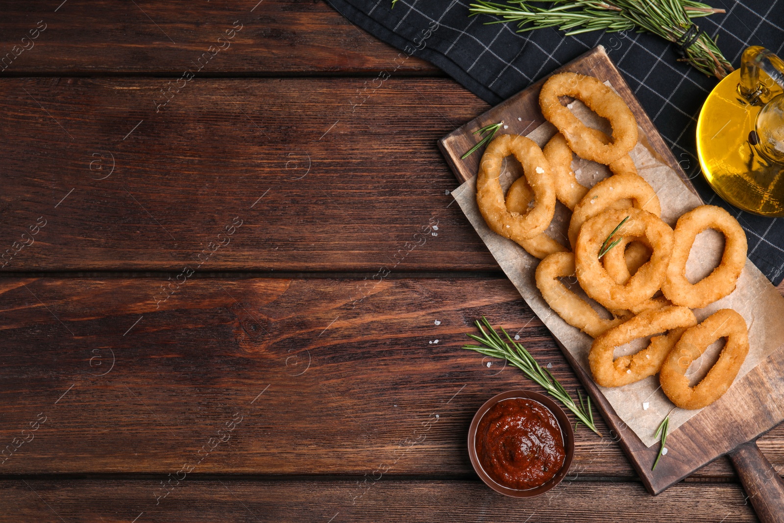 Photo of Fried onion rings served on wooden table, flat lay. Space for text