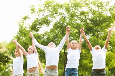 Photo of Group of children holding hands up in park. Volunteer project