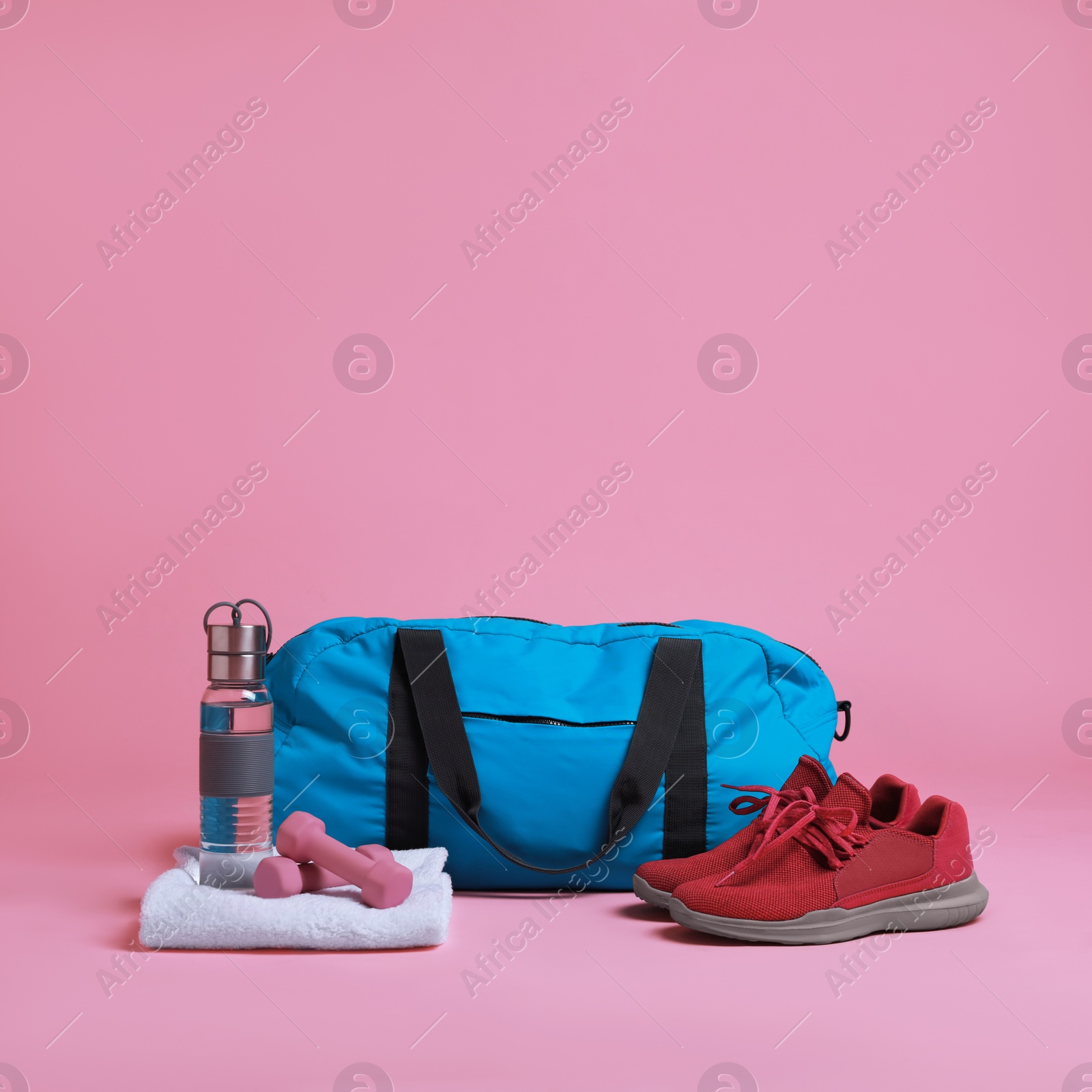 Photo of Blue gym bag and sports accessories on pink background