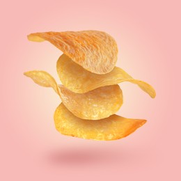 Stack of tasty potato chips falling on pink background
