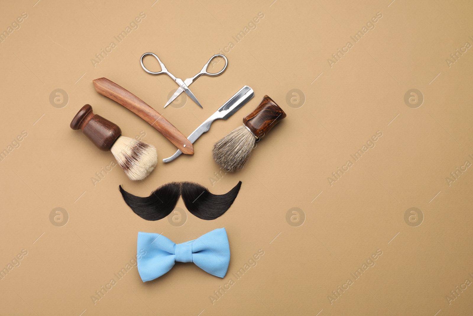 Photo of Artificial moustache and barber tools on beige background, flat lay. Space for text