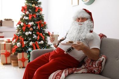 Photo of Authentic Santa Claus with milk and cookies indoors