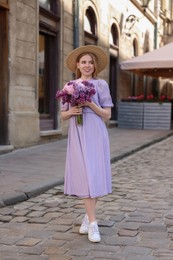 Beautiful woman with bouquet of spring flowers on city street