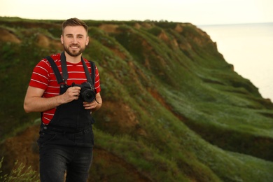 Male photographer with professional camera on green hill