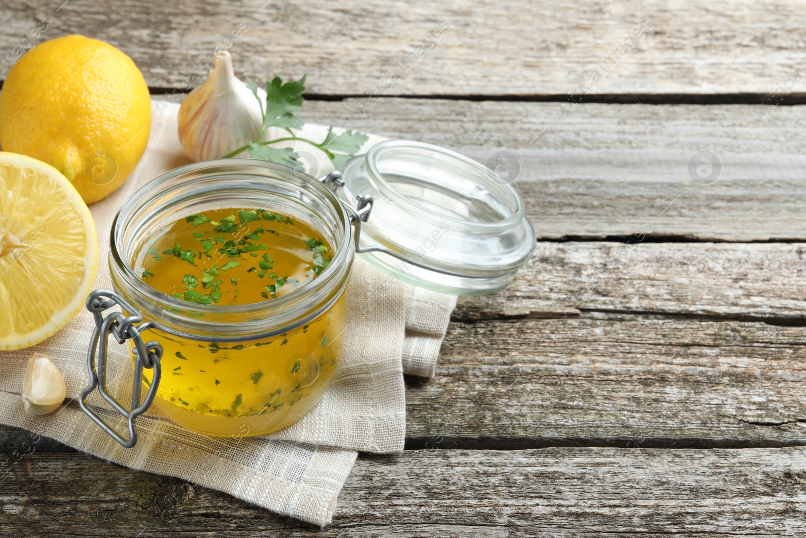 Photo of Jar with lemon sauce and ingredients on wooden table, space for text. Delicious salad dressing